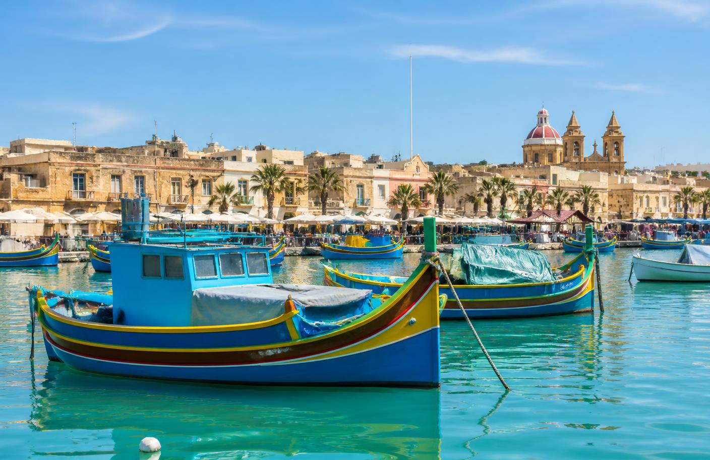 Traditional Maltese luzzu boats moored in a turquoise harbour